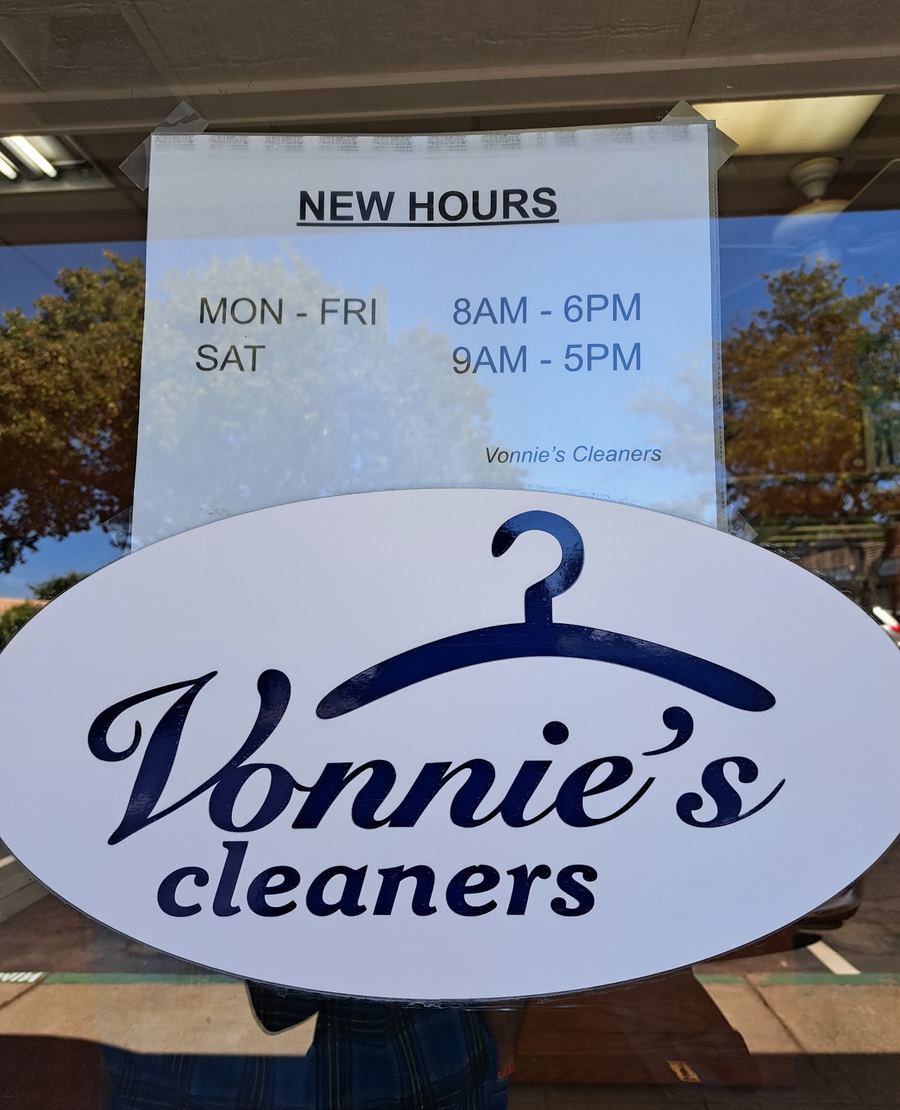 A notice in the door reading New Hours: Mon–Fri 8 AM–6 PM, Sat 9 AM–5 PM, above an oval Vonnie's cleaners sign with a hanger.