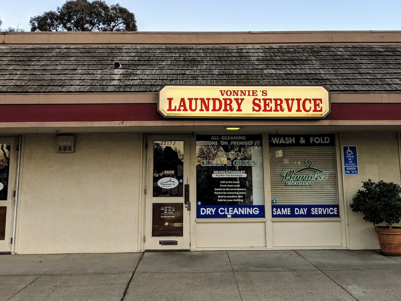 The Vonnie's storefront at 2217 J: a lit 'Vonnie's Laundry Service' sign above windows reading Dry Cleaning, Wash & Fold and the Vonnie's cleaners hanger logo.